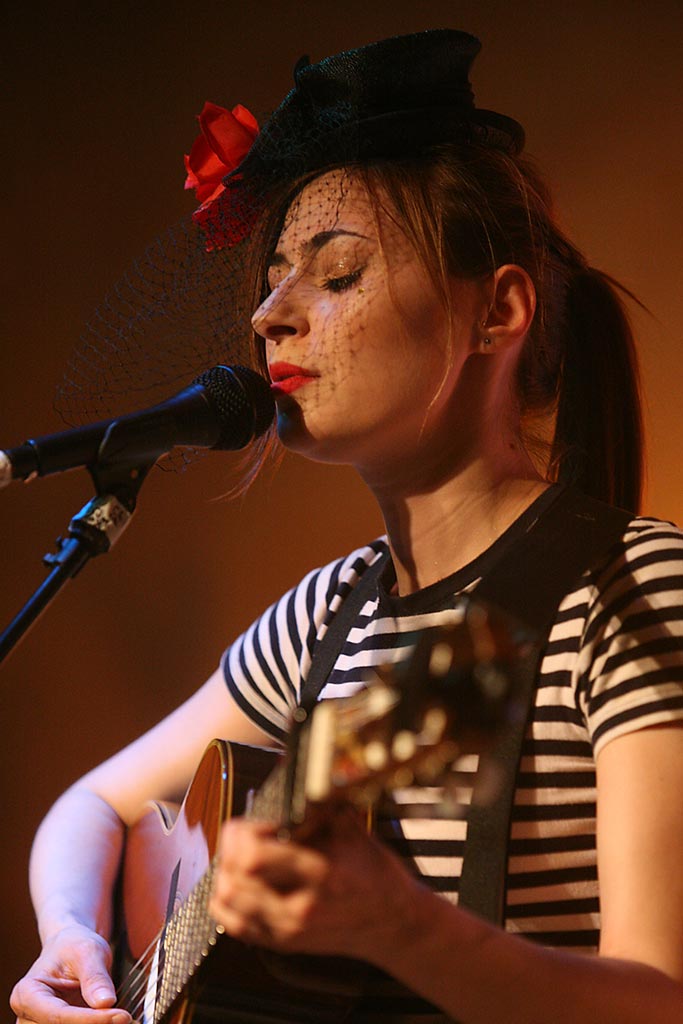 Image of Manchester UK based singer-songwriter Zoe Kyoti singing and playing an acoustic guitar. Copyright Zoe Kyoti - Official Site